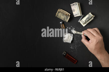 Hand man pour heroin hidden in dollar on dark floor background. Dangerous and illegal concept Stock Photo