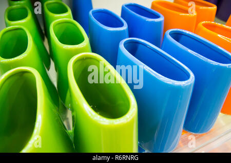 Multi-colored ceramic toothbrush stands on the shelf Stock Photo