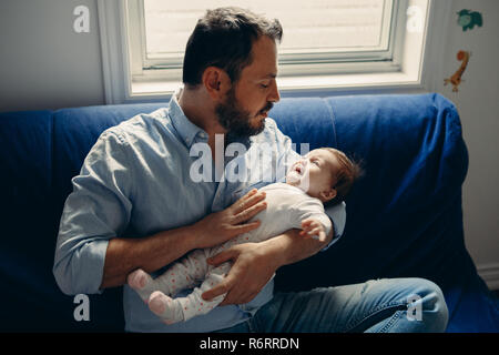 Portrait of middle age Caucasian father trying to calm down newborn baby. Male man parent holding child on his hands. Authentic lifestyle documenatry  Stock Photo