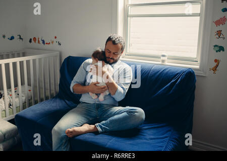 Portrait of middle age Caucasian father trying to calm down newborn baby. Male man parent holding child on his hands. Authentic lifestyle documenatry  Stock Photo