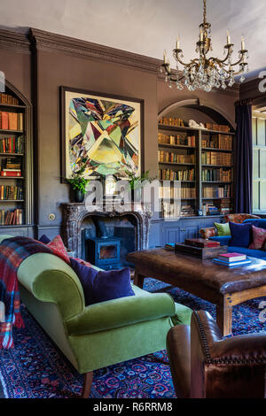 Modern artwork above marble fireplace with recessed bookcases in 18th century Goodnestone mansion Stock Photo