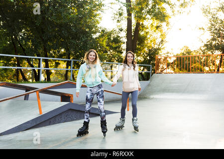 Two pretty young girls on on roller skates spending time at the skate park Stock Photo