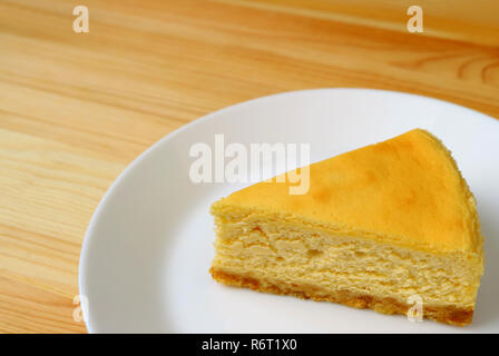 Plate of mouthwatering creamy yellow plain baked cheesecake served on wooden table Stock Photo