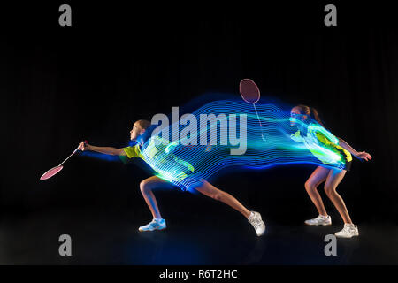 The one caucasian young teenager girl playing badminton at studio. The female teen player on black background in motion with flashes of light Stock Photo