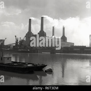 1950s, historical, looking south across the river Thames, a view of a working Battersea Power Station , Battersea, London, England, with smoke emerging from its iconic four chimneys. A coal-fired power station in Nine Elms, Battersea, Wandsworth, it was built for the London Power Company and started production in 1933 (A Station).  Battersea B Power station, constructed between 1937-1941 and finally completed in 1955, was built to a near identical design to 'Battersea A' which gives the building it's iconic four-chimney structure. Stock Photo