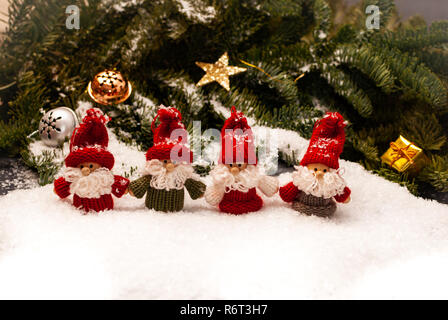 A group of four christmas dwarfs standing in the snow in front of the decorated forest Stock Photo