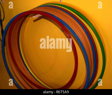 hula hoops made of different materials and colors hanging on a hook in front of yellow background, different hula hoops Stock Photo