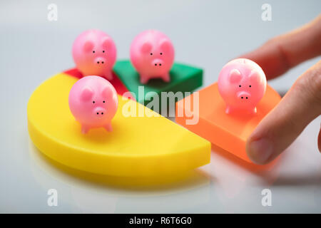 Person Placing Last Piece Into Pie Chart With Piggy Bank Stock Photo