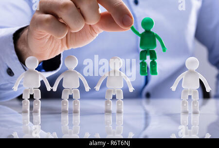 Person Selecting Green Figure Amongst White Human Figures Stock Photo