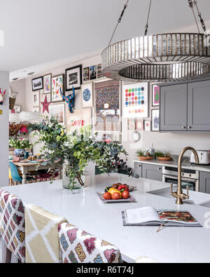 Downton chandelier above reconfigured kitchen with upcycled bar stool seating Stock Photo