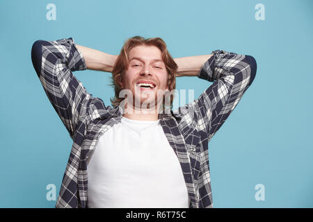 The happy business man standing and smiling against blue background. Stock Photo