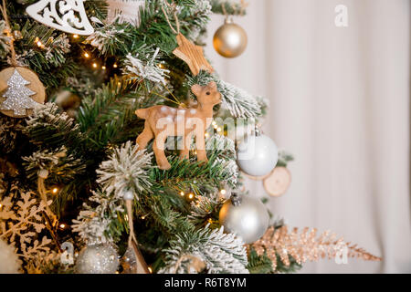 Interior room decorated in Christmas style. No people. Neutral pastel colors. Home comfort of modern cozy home.Christmas tree and Christmas decorations with deer, sparking, glowing. Happy New Year and Xmas theme Stock Photo