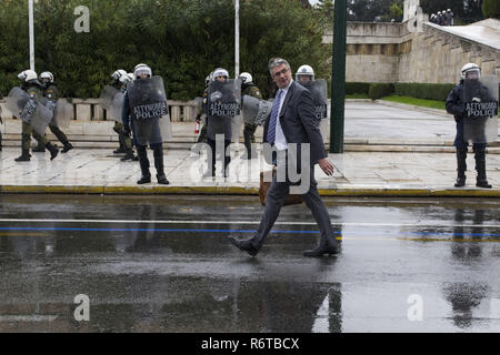 Athens, Greece. 6th Dec, 2018. A businessman passes by riot police securing the area around the Parliament. Students demonstrated to commemorate Alexis Grigoropoulos, the 15 year old student who was gunned down by a police officer in Exarchia, central Athens on December 6th, 2008. Credit: Nikolas Georgiou/ZUMA Wire/Alamy Live News Stock Photo