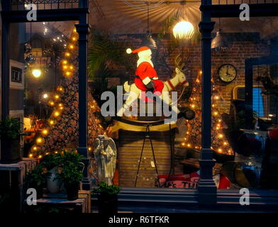 Worthing, Sussex, England. 6th December, 2018. Santa's rockin' Reindeer.Festive Christmas season antique shop window display in Rowlands Road today with vintage artifacts and Santa Claus riding an old rocking Reindeer.  Photo: Jonathan Eastland/Ajax/Alamy Live News. Stock Photo