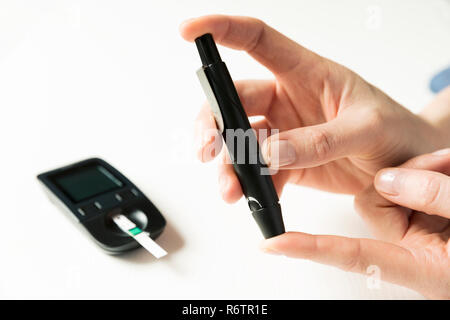 Diabetes checking blood sugar level. Woman using lancelet and glucometer at home Stock Photo