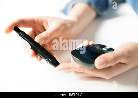 Diabetes checking blood sugar level. Woman using lancelet and glucometer at home Stock Photo