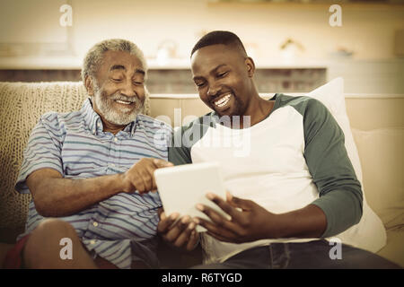 Smiling father and son using digital tablet in living room Stock Photo
