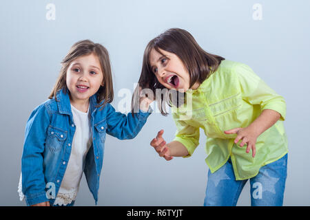 conflict between sisters, younger sister pulls the hair older sister. Stock Photo