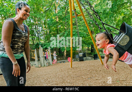 Nailah Wagner pushes her daughter, 10-month-old Emery Wagner, in a swing at Candler Park, June 4, 2014, in Atlanta, Georgia. Stock Photo