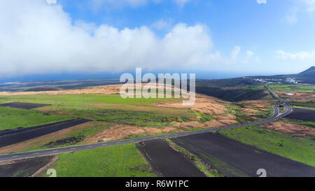 Aerial landscape of empty country road through agriculture farms, volcanic fields in Lanzarote, Canary Islands, Spain . Stock Photo