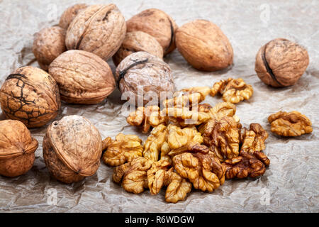 Walnut kernels with whole nuts in background, selective focus. Stock Photo