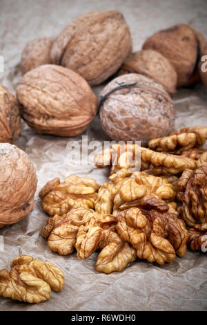 Walnut kernels with whole nuts in background, selective focus. Stock Photo