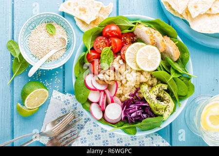 Bowl with grilled chicken meat, bulgur  and fresh vegetable salad of radish, tomatoes, avocado, kale and spinach leaves. Healthy and delicious summer  Stock Photo