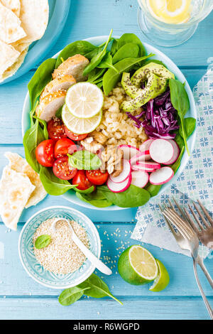 Bowl with grilled chicken meat, bulgur  and fresh vegetable salad of radish, tomatoes, avocado, kale and spinach leaves. Healthy and delicious summer  Stock Photo