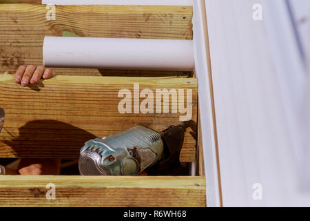 Man building a wooden patio with hammering screwing together beams Stock Photo