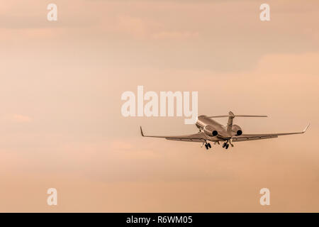 An executive business jet aeroplane taking off and heading out in to the sky and clouds, early evening sunset. Stock Photo