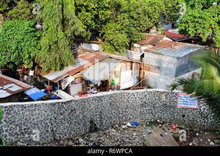 Huts of a slum next to a polluted watercourse in Quezon City, Metro Manila, Philippines Stock Photo