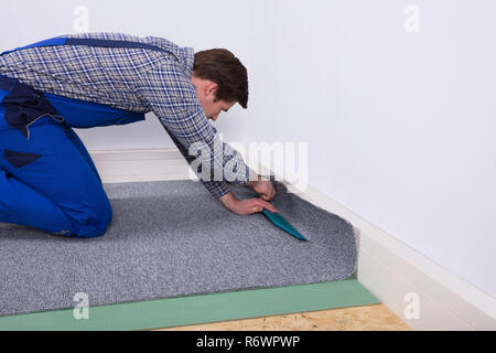 Worker Fitting Carpet On Floor Stock Photo