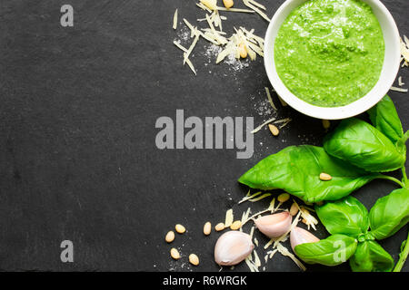 Pesto sauce in a bowl with pine nuts, parmesan and garlic over black stone background. top view with copy space Stock Photo
