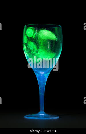 Thumb print fingerprints on wine glass showing up under blacklight ultraviolet light as forensic evidence of identity to suspect Stock Photo