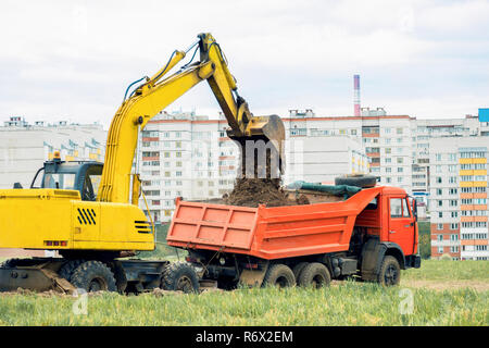 Excavator pours earth into a dump truck. Earthwork Stock Photo