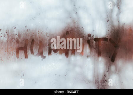 Humidity word written on wet window. High level of dampness in apartment. Stock Photo
