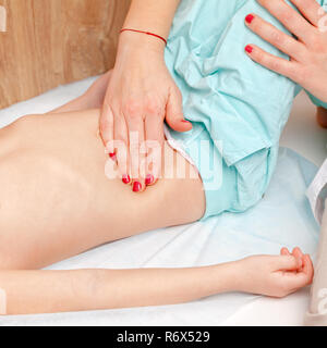 Female pediatrician or health care practitioner examines little girl's abdomen. Doctor performing manual palpation. Child physical examination concept Stock Photo