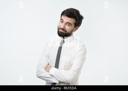 Smiling handsome hispanic man in white shirt crossing hands. Stock Photo