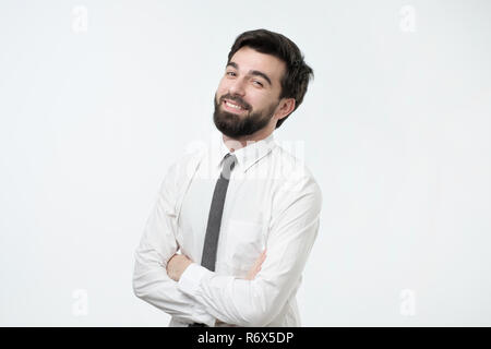 Smiling handsome hispanic man in white shirt crossing hands. Stock Photo