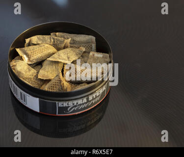 Close up of plastic tin of pouches of typically Swedish snus. Snus is a  variant originating from dry snuff, made of smokeless pulverised tobacco  that is placed between upper lip and gum