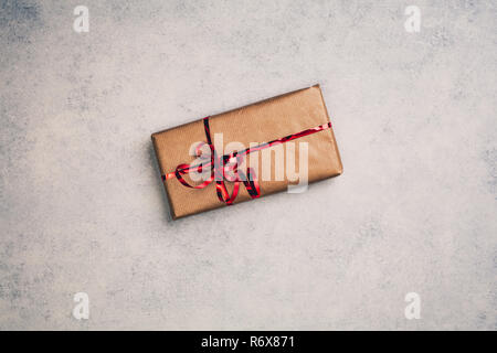 Gift or present in brown paper box with red ribbon, above view. Top centered closeup view with copy space. Stock Photo
