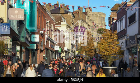 WINDSOR, ENGLAND - NOVEMBER 2018: Street in Windsor town centre crowded with Christmas shoppers. Windsor Castle is in the background. Stock Photo