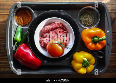 Ground beef, with peppers and other ingredients  on baking pan with wooden background top view Stock Photo