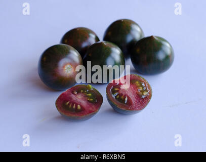 Black cherry tomatoes in group with a halved tomato in the front Stock Photo