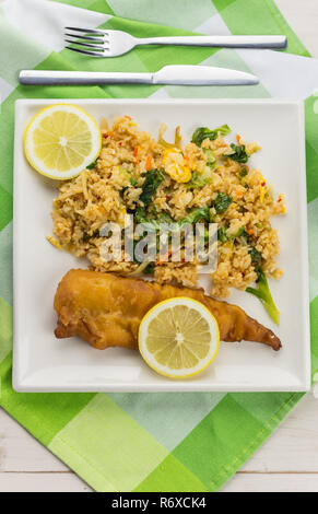 Battered and fried cod with rice and vegetables on a white plate Stock Photo