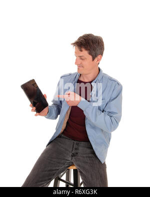 Young man sitting on chair pointing to his tablet Stock Photo
