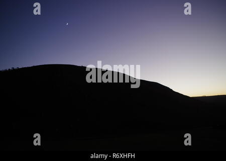 Silhouetted Valley Top Ridgeline at Twilight, against a  Purple Sky with Moon. Valley of the Rocks, Exmoor National Park, North Devon, UK. Stock Photo