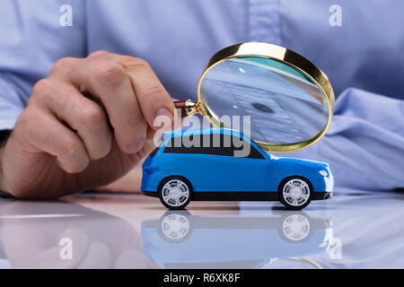 Person Holding Magnifying Glass Over Car Stock Photo