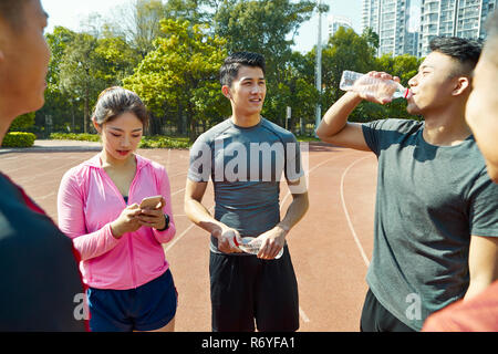 group of young asian athletes talking and relaxing on track after training. Stock Photo