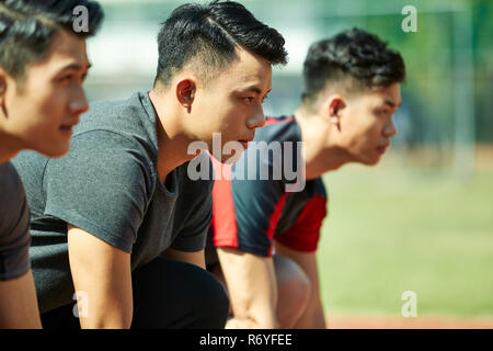 young asian track and field athletes sprinters setting on starting line. Stock Photo